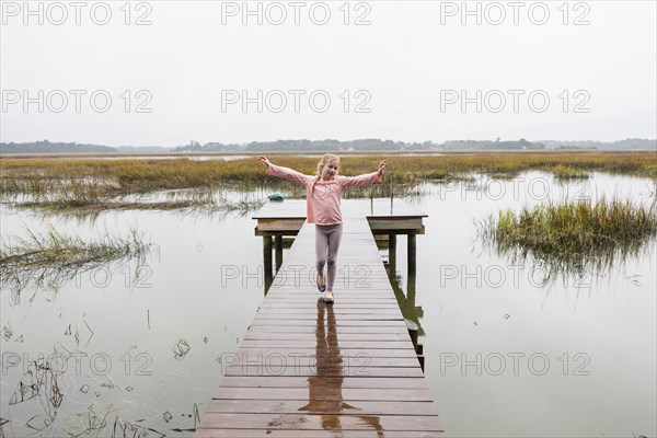 Caucasian girl standing on wooden dock over lake