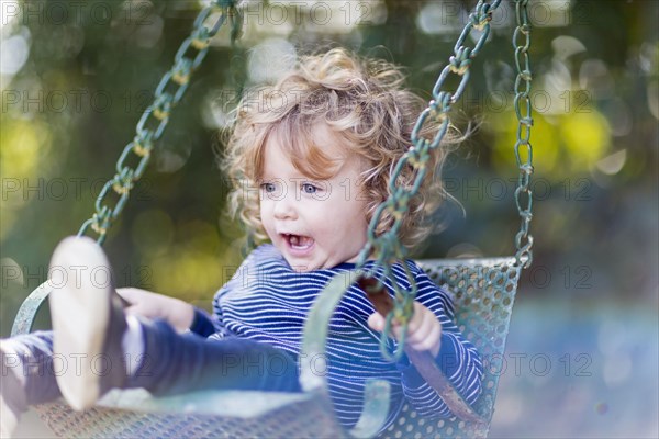 Caucasian baby boy sitting on swing