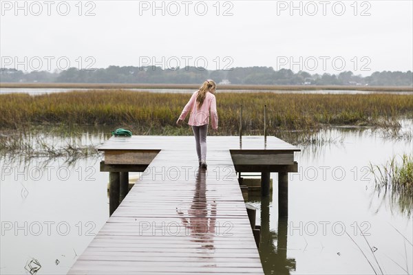 Caucasian girl walking on wooden dock