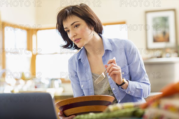 Hispanic business owner eating salad in home office