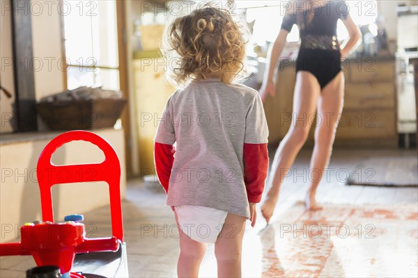 Caucasian baby boy playing with older sister in kitchen