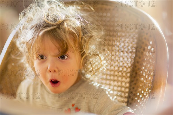 Caucasian baby boy gasping in wicker chair