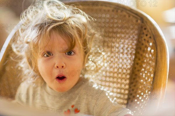 Caucasian baby boy gasping in wicker chair