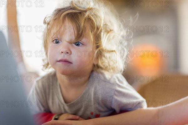 Caucasian baby boy peering at computer screen
