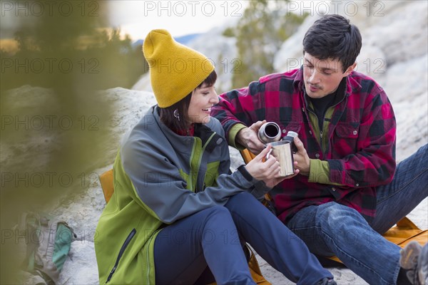 Couple sharing coffee on rock formations