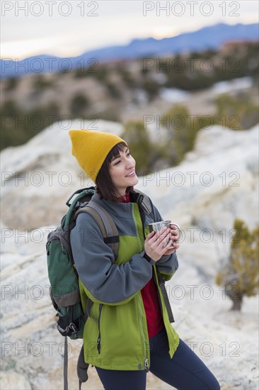 Hispanic woman drinking coffee on rock formations