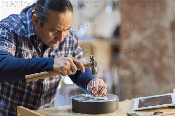 Native American artist hammering metal in studio