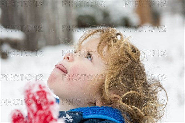 Caucasian boy catching snowflakes on tongue