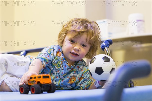 Caucasian boy playing on hospital bed