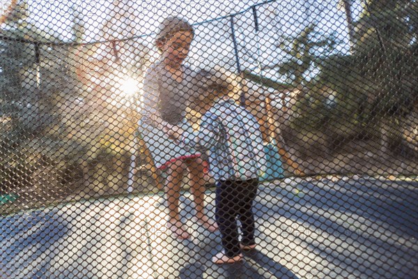 Caucasian brother and sister jumping on trampoline