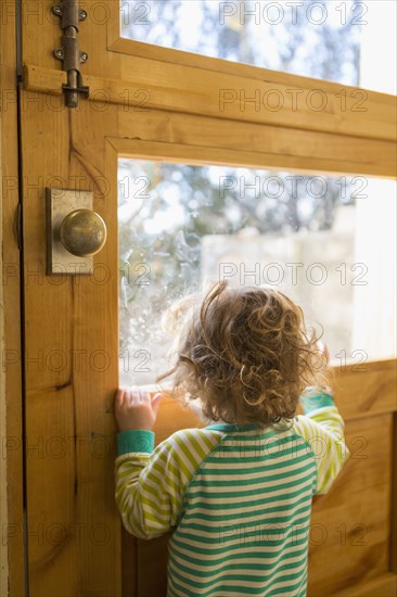 Caucasian boy looking out door window