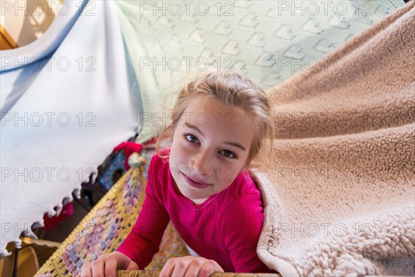Caucasian girl playing in blanket fort