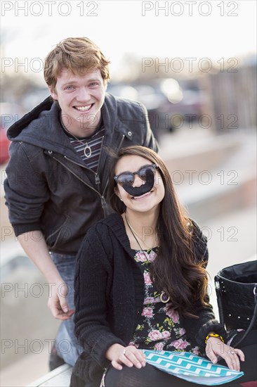 Teenage couple playing with fake mustache