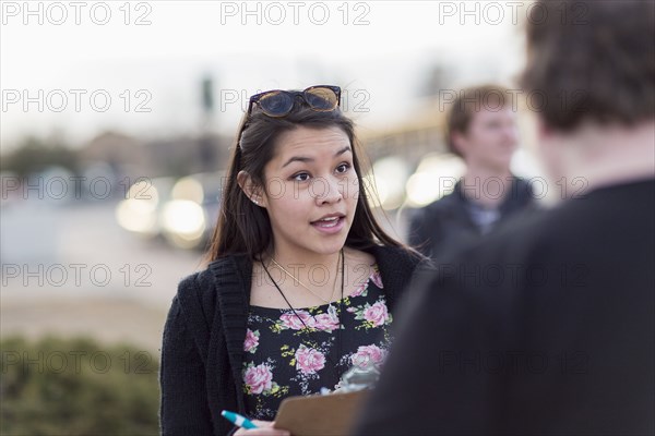 Canvasser with clipboard talking to man