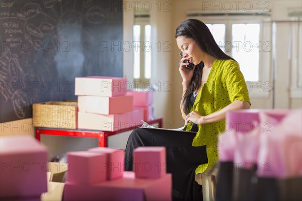 Mixed race businesswoman talking on telephone in office