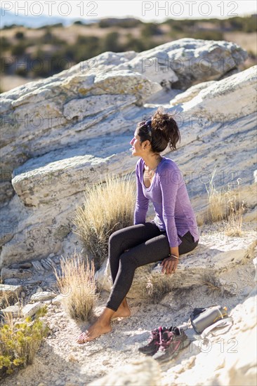 Hispanic woman sitting on rocky hilltop