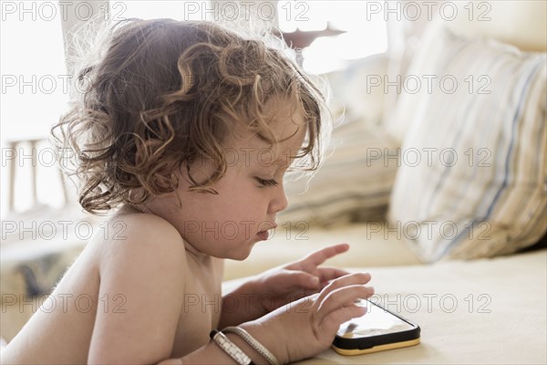 Caucasian baby boy playing with cell phone on sofa