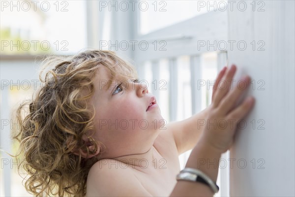 Caucasian baby boy leaning on wall