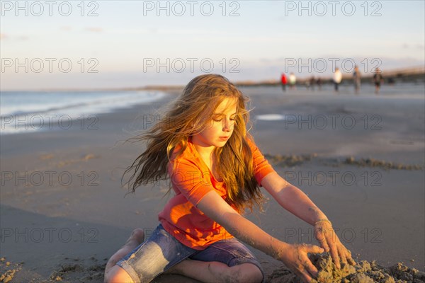 Caucasian girl building sandcastle on beach