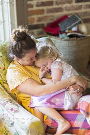 Caucasian mother holding daughter in armchair