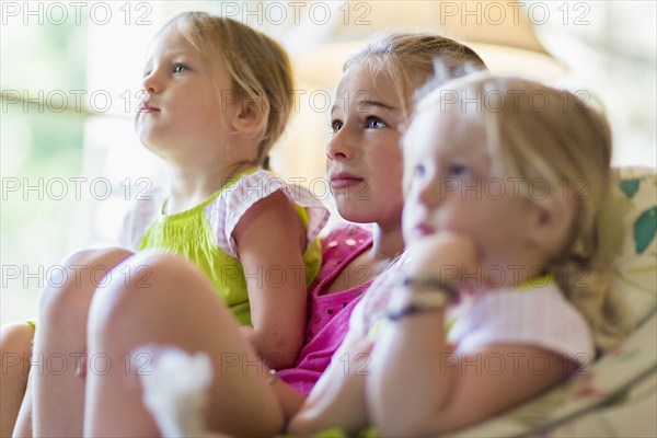 Caucasian girls watching television in armchair