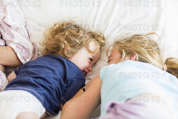 Caucasian brother and sister playing on bed