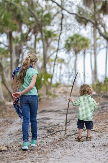 Caucasian brother and sister walking on dirt path