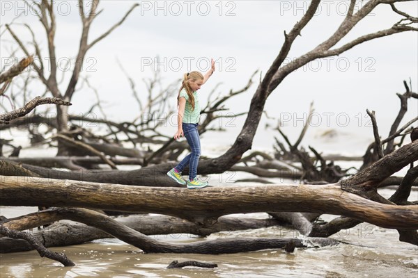 Caucasian girl walking on driftwood tree