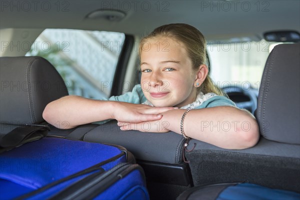 Caucasian girl sitting in car back seat on road trip