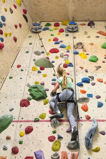 Caucasian girl climbing rock wall indoors