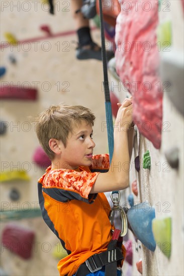 Caucasian boy climbing rock wall indoors