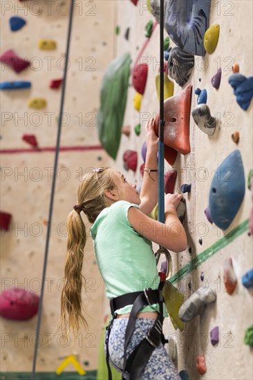 Caucasian girl climbing rock wall indoors