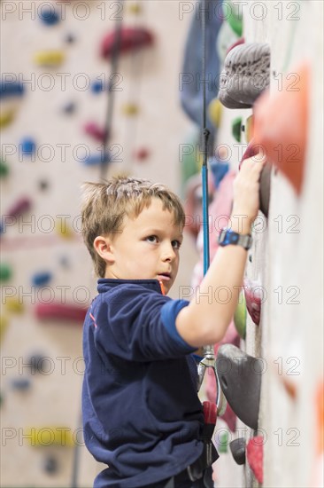 Caucasian boy climbing rock wall indoors