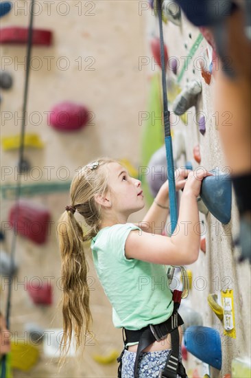 Caucasian girl climbing rock wall indoors