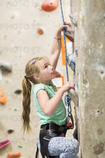 Caucasian girl climbing rock wall indoors