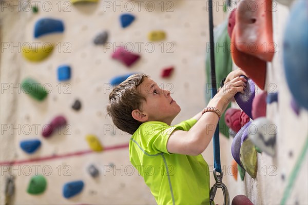 Caucasian boy climbing rock wall indoors