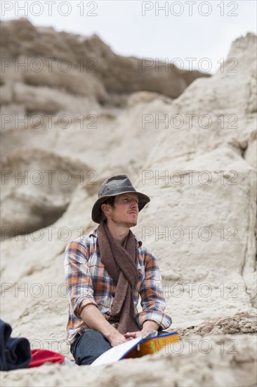 Caucasian hiker sitting on rock formation in desert