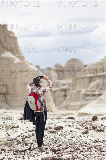 Caucasian hiker photographing desert rock formations