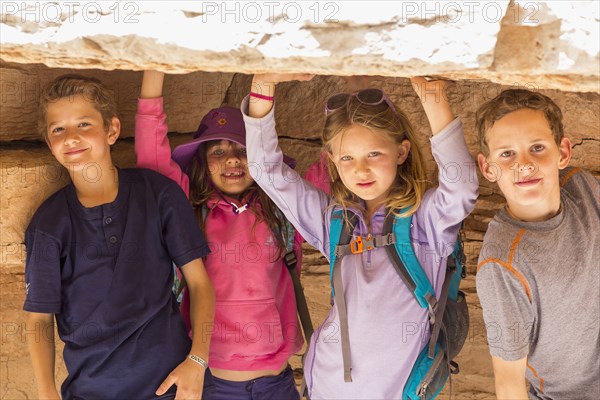 Children crouching under rock formation