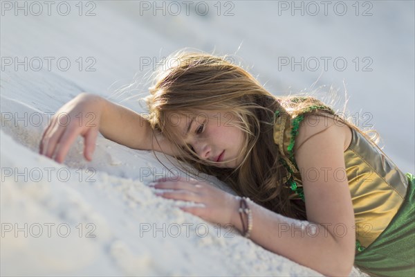 Caucasian girl laying on desert sand dune