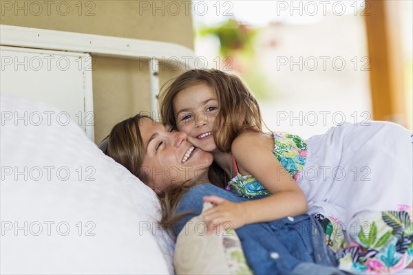 Mother and daughter hugging on bed