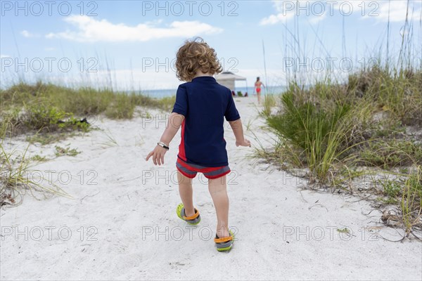 Caucasian baby boy walking on beach