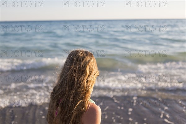 Caucasian girl watching waves on beach