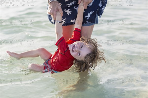Caucasian mother and baby son playing on beach
