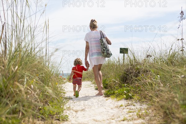 Caucasian mother and baby son walking on beach