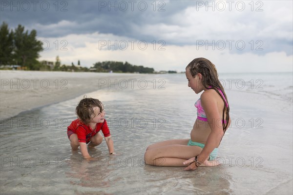 Caucasian brother and sister playing in ocean