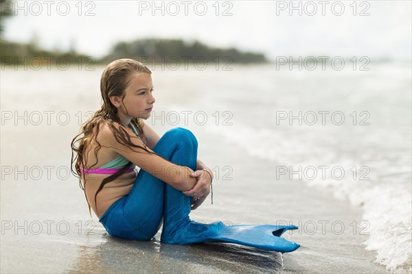 Caucasian girl wearing mermaid fin on beach