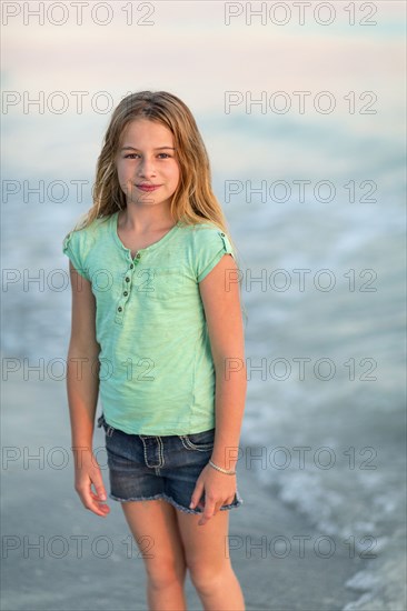 Caucasian girl standing in ocean waves