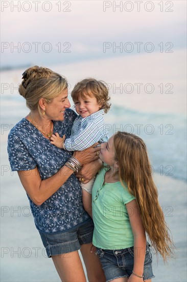 Caucasian mother and children playing on beach