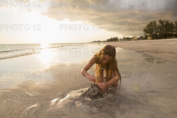 Caucasian girl building sandcastle on beach